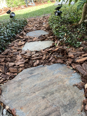 Stepping-stone path through a fresh pine bark mulch bed