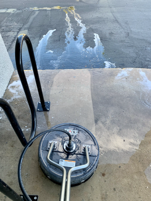 Surface cleaner pressure washing a concrete driveway, with clean and dirty sections side by side